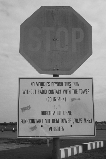 Verwittertes Stoppschild mit Angabe der Tower-Funkfrequenz